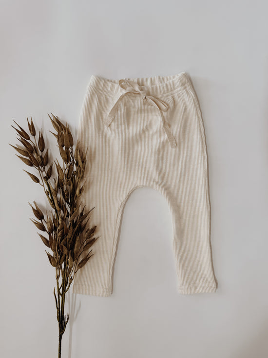 Infant waffle pants in a cream color with ties for decoration.