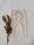 Infant waffle pants in a cream color with ties for decoration.