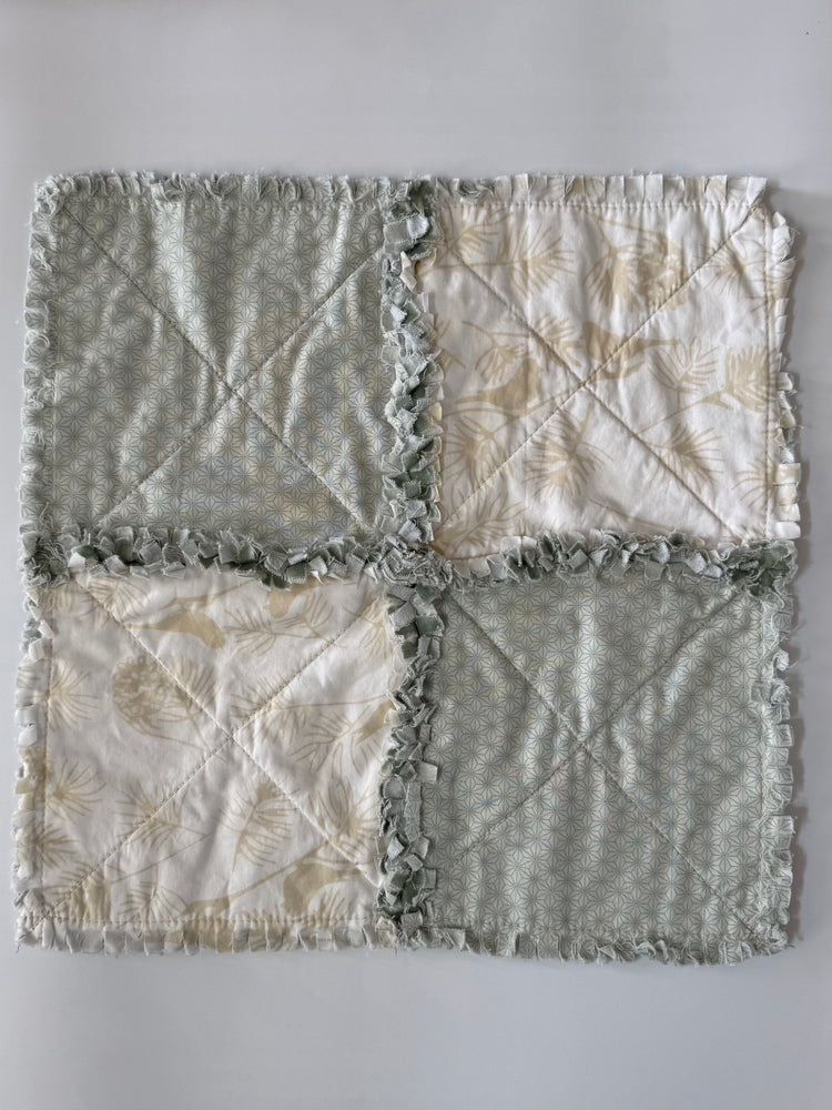 Quilt with a patchwork design featuring gray and beige colors on a white background