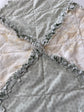 Close-up of a quilt with ruffled edges in teal and cream bird pattern. 