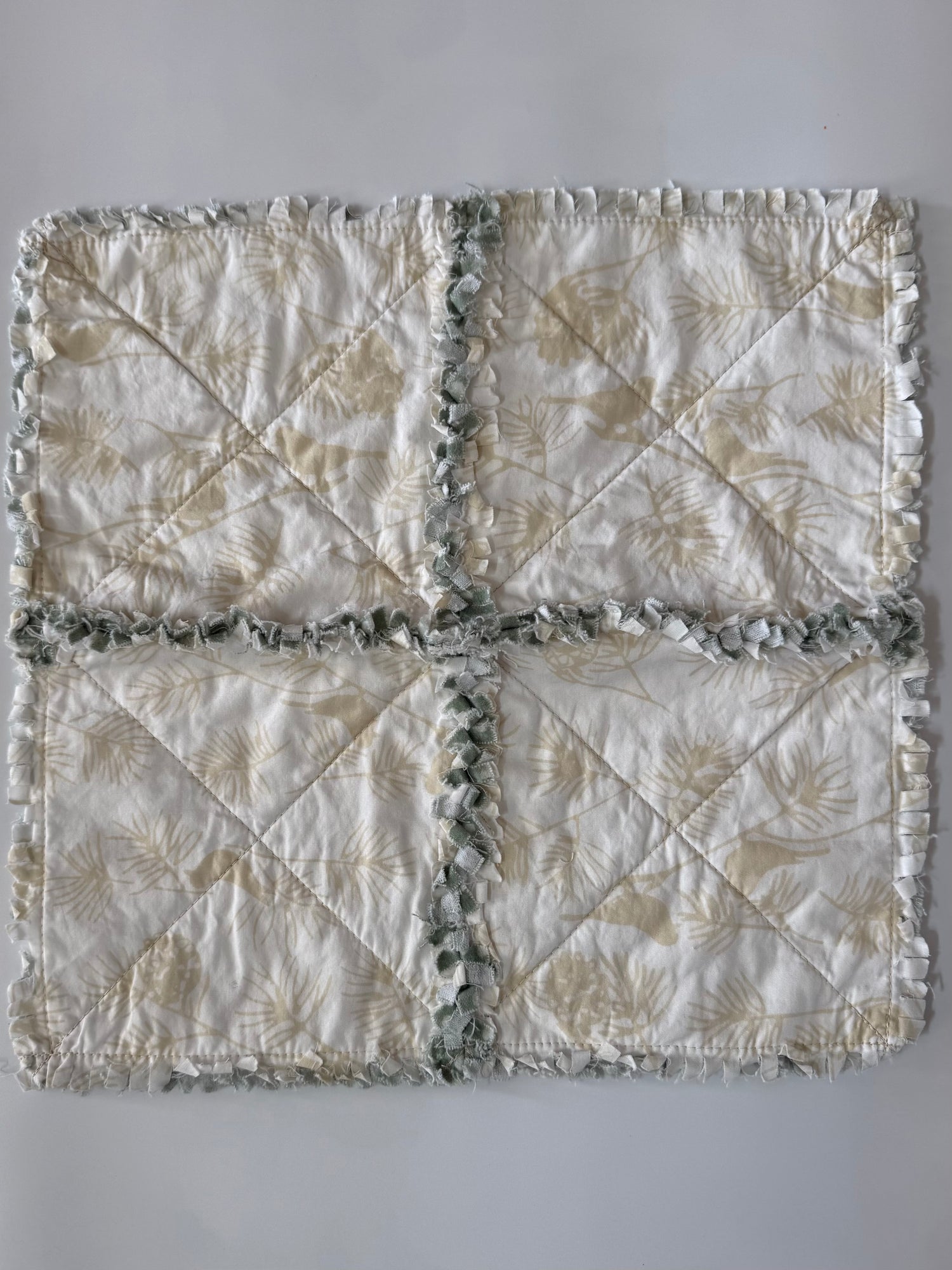 Quilt with leaf and bird pattern on a plain background