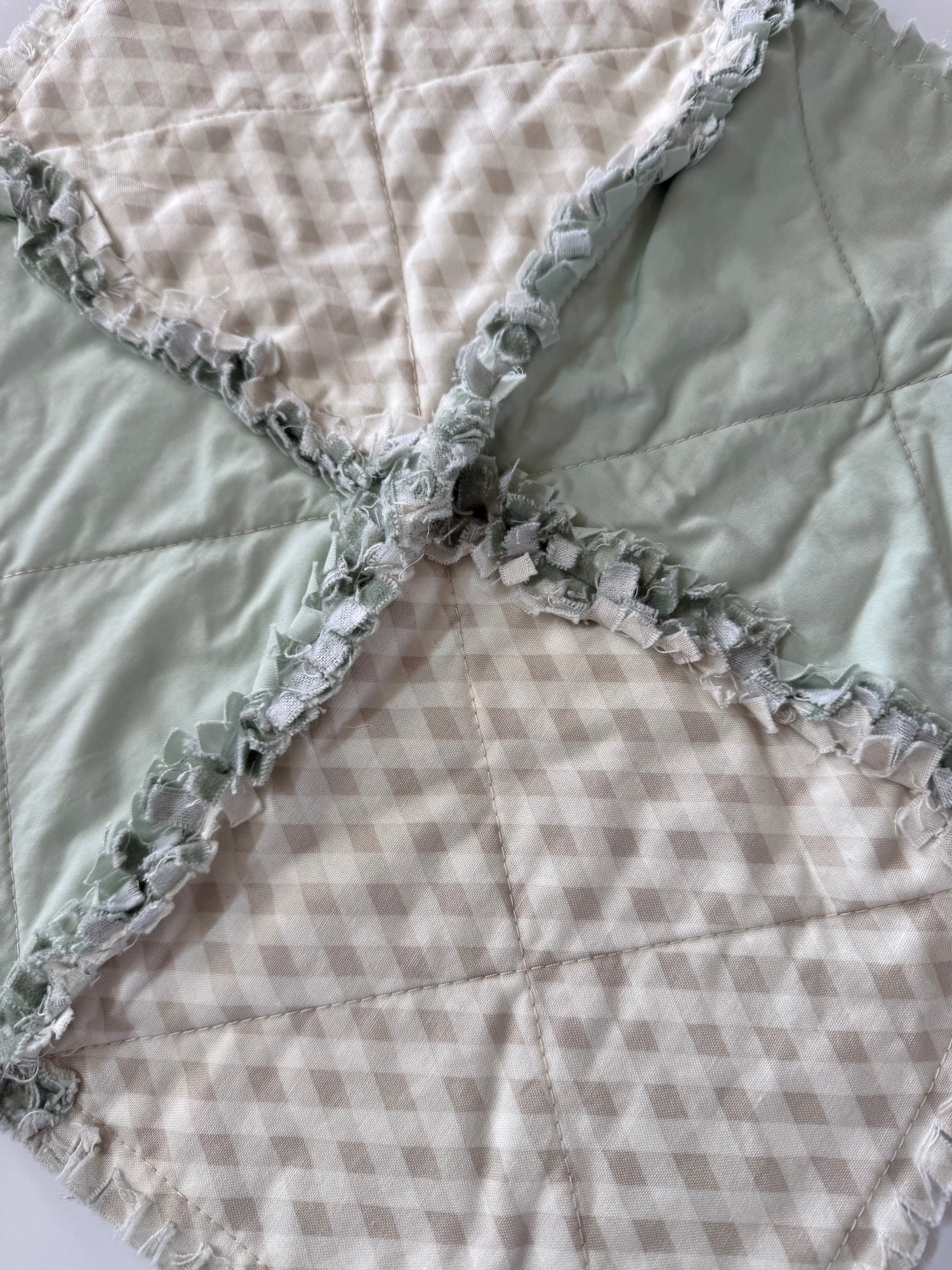 Quilt with checkered pattern and ruffled edge on a white background