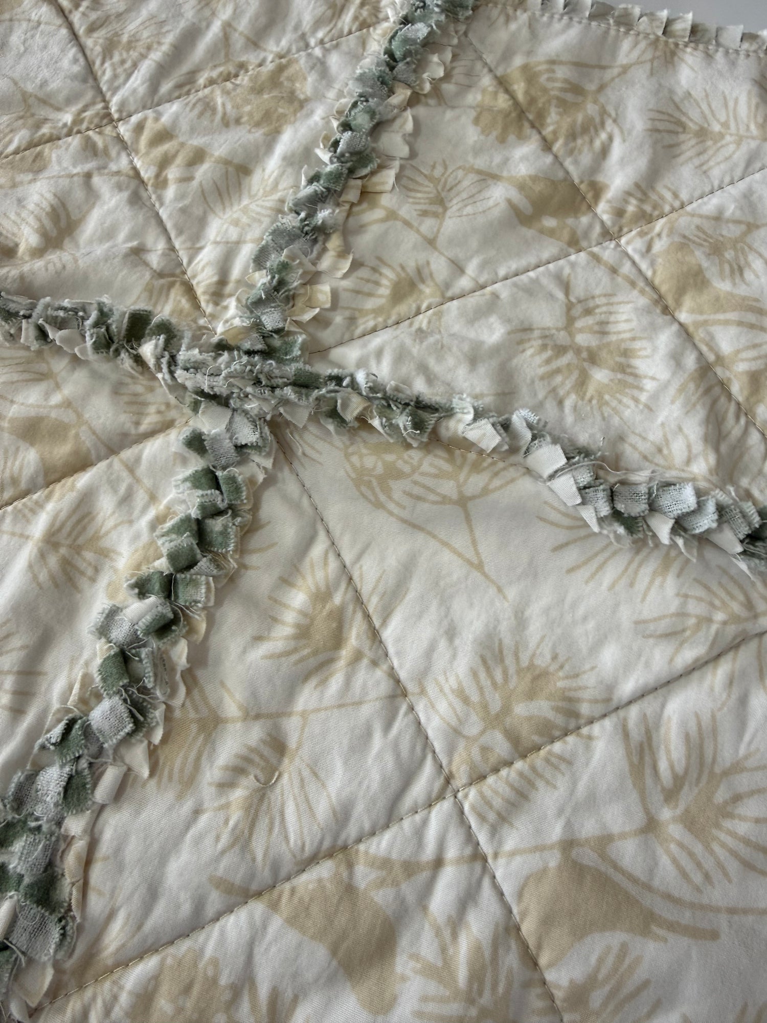 Close-up of a quilt with leaf and bird patterns. 