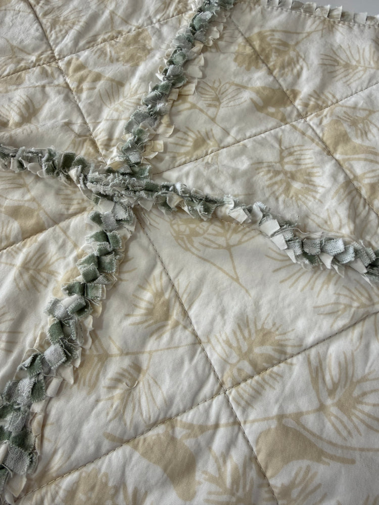 Close-up of a quilt with leaf and bird patterns. 