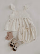 Baby outfit set with dress, bloomers, and socks on a light gray background